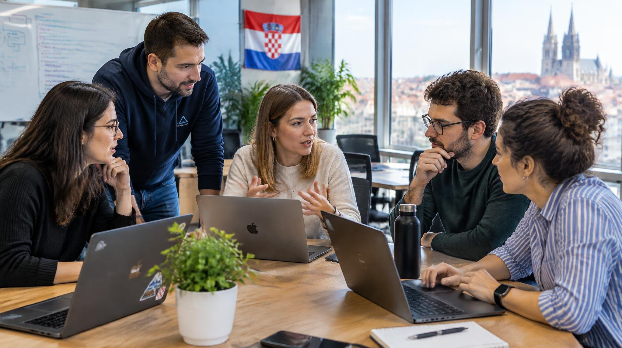 Software team collaborating around laptops in a bright office